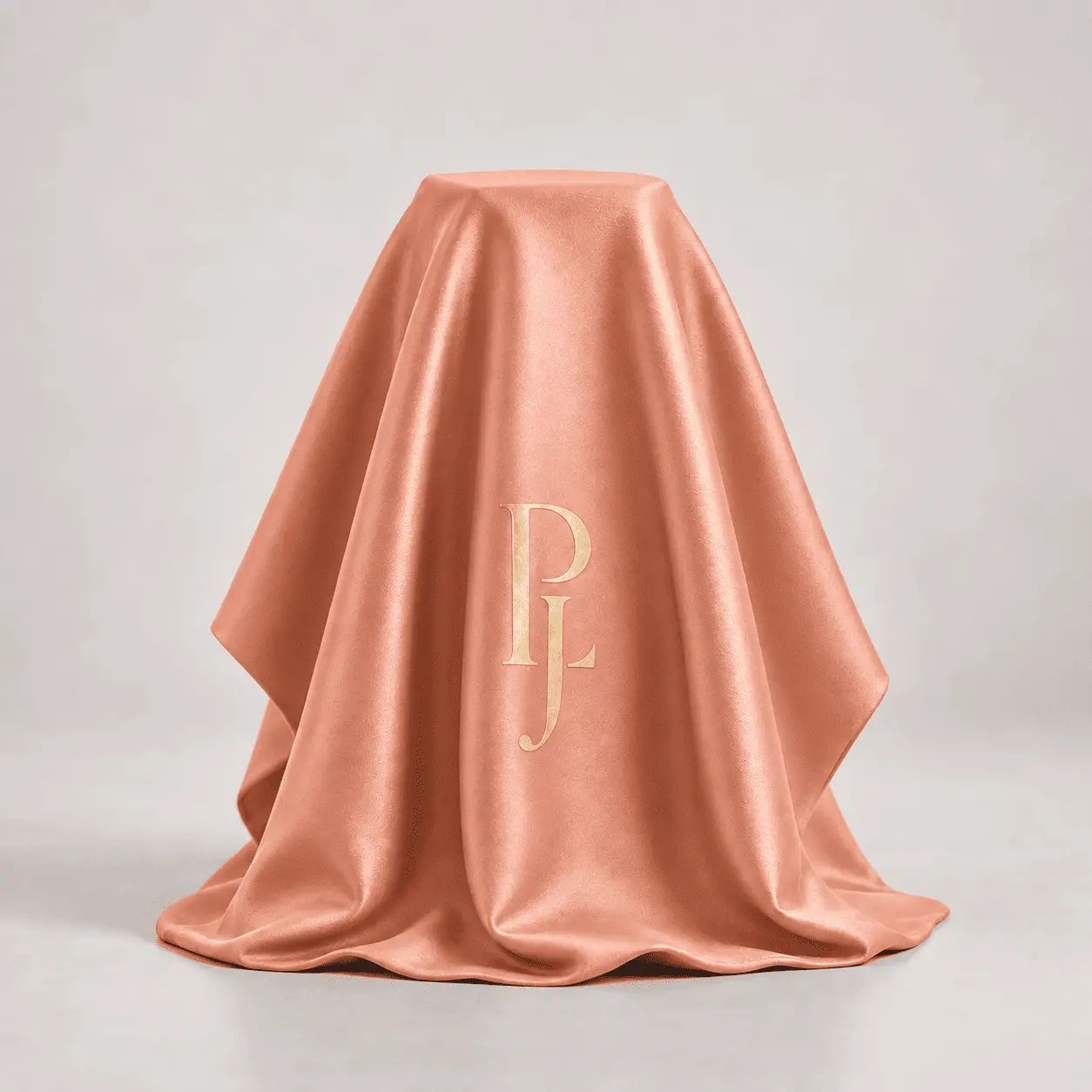A bottle hidden beneath coral silk, monogrammed in gold.